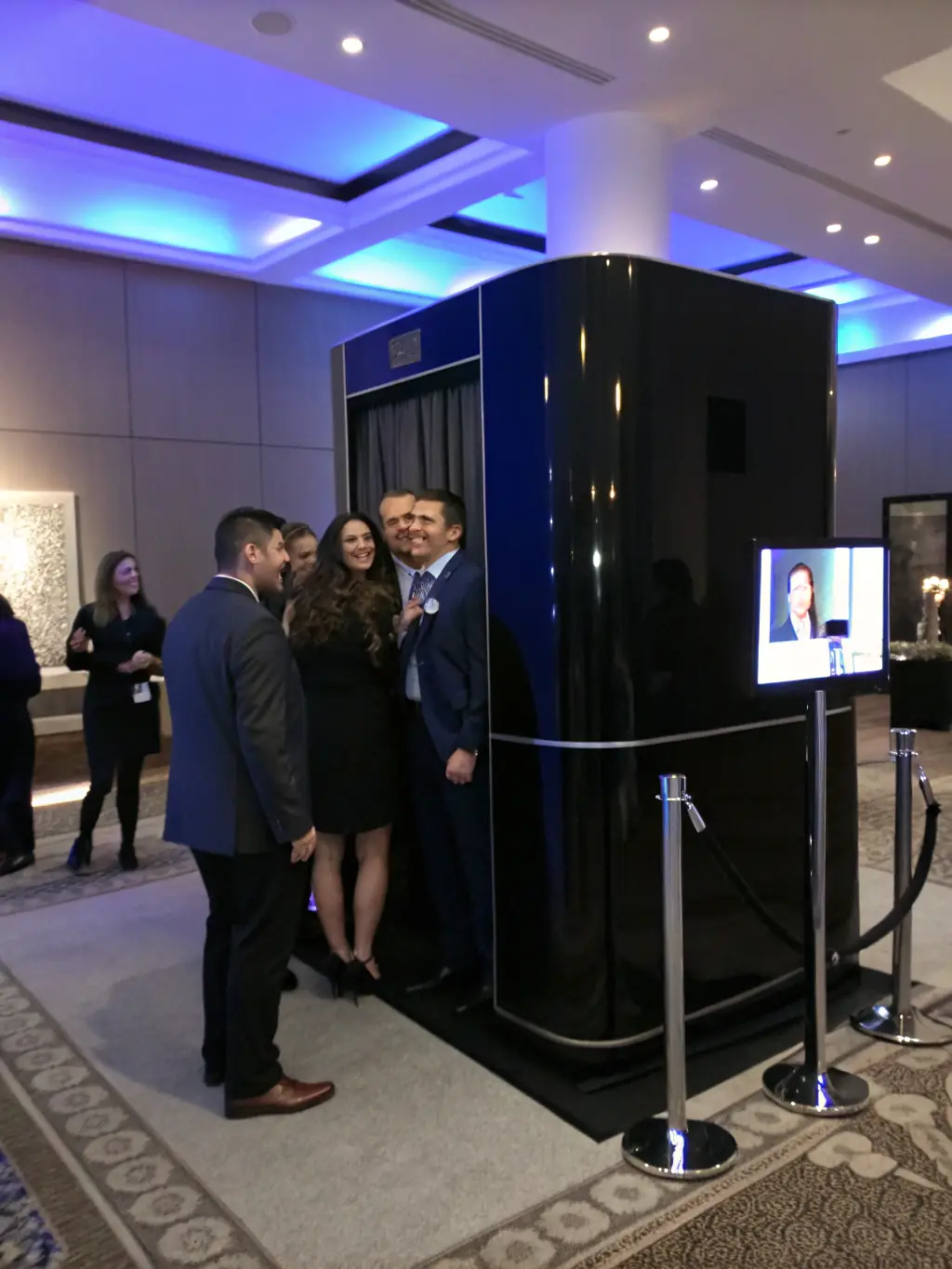 A lively corporate event with attendees taking fun and professional headshots inside a Snapcave booth, branded with the company logo.