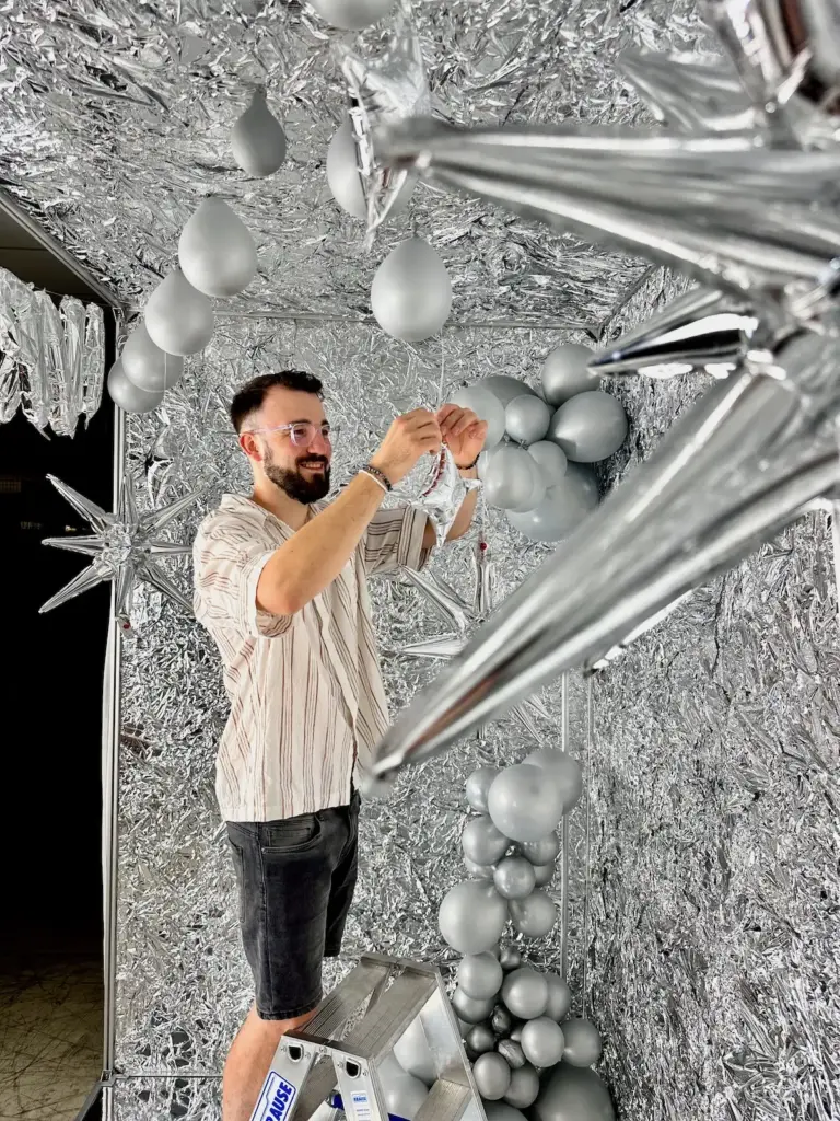 Glänzende Innenansicht der Snapcave Silver Star Fotobox mit Spiegelboden, silberner Deko-Wand und Ballons