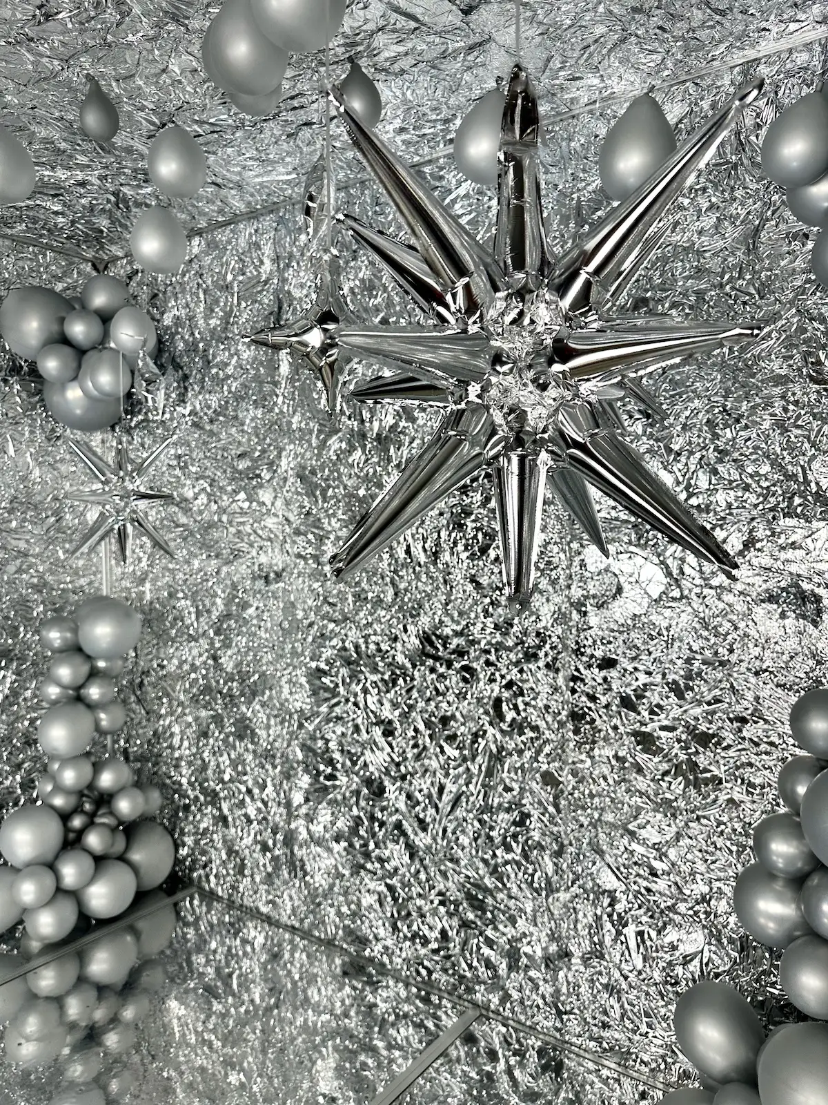 Glänzende Innenansicht der Snapcave Silver Star Fotobox mit Spiegelboden, silberner Deko-Wand und Ballons